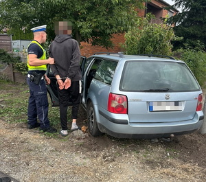 rozbity samochód; policjant prowadzący zatrzymanego do radiowozu