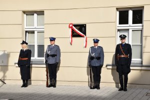 zdjęcie kolorowe, dwóch policjantów w mundurach i dwóch rekonstruktorów w mundurach z okresu międzywojennego przy tablicy pamiątkowej